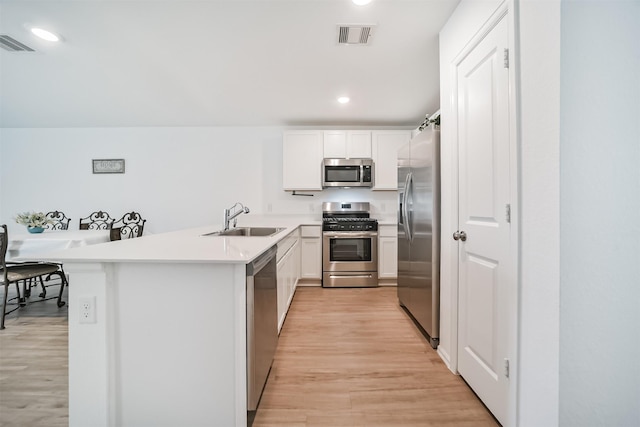 337 Riverwood Village Ln, Sealy, TX 77474 - kitchen featuring appliances with stainless steel finishes, a sink, light wood-style flooring, a peninsula, and recessed lighting