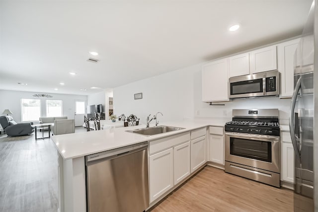 337 Riverwood Village Ln, Sealy, TX 77474 - kitchen featuring appliances with stainless steel finishes, a sink, a peninsula, open floor plan, and white cabinets