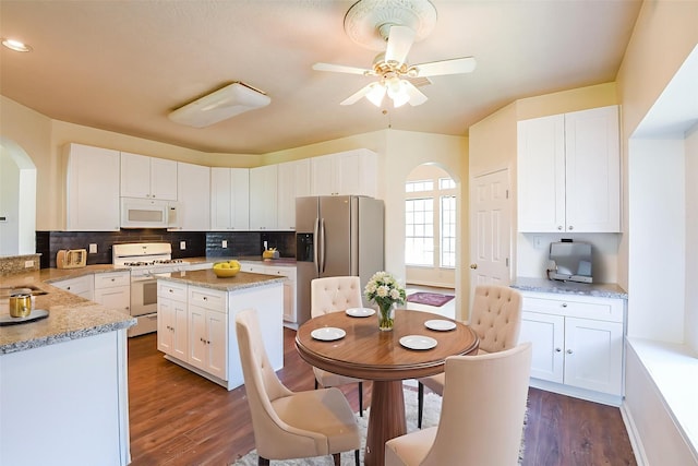 3550 Beacons Vw, Friendswood, TX 77546 - kitchen featuring white appliances, arched walkways, white cabinets, dark wood finished floors, and decorative backsplash