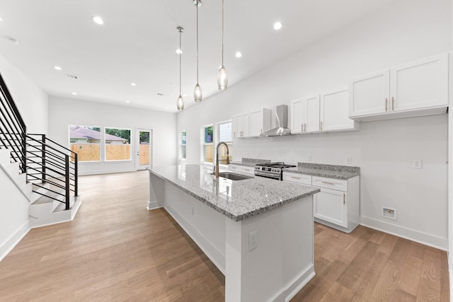 4710 Gunter St, Houston, TX 77020 - kitchen featuring a sink, stainless steel range with gas cooktop, wall chimney exhaust hood, white cabinetry, and recessed lighting