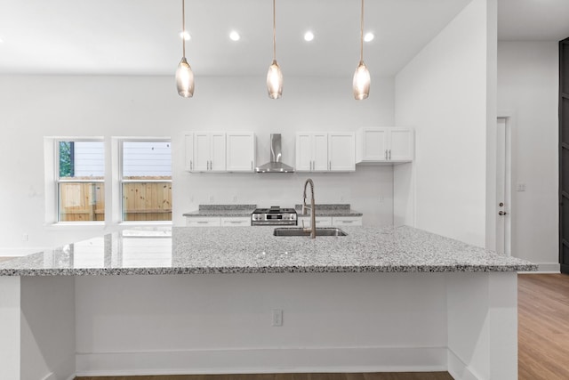 4710 Gunter St, Houston, TX 77020 - kitchen with wall chimney exhaust hood, a sink, gas range, white cabinets, and a spacious island