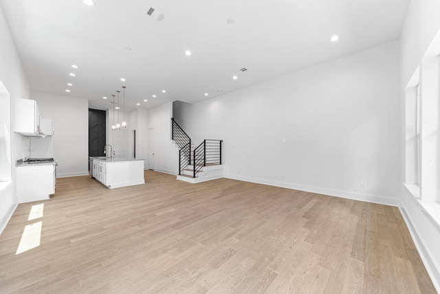 4710 Gunter St, Houston, TX 77020 - unfurnished living room featuring light wood finished floors, stairs, a sink, baseboards, and recessed lighting