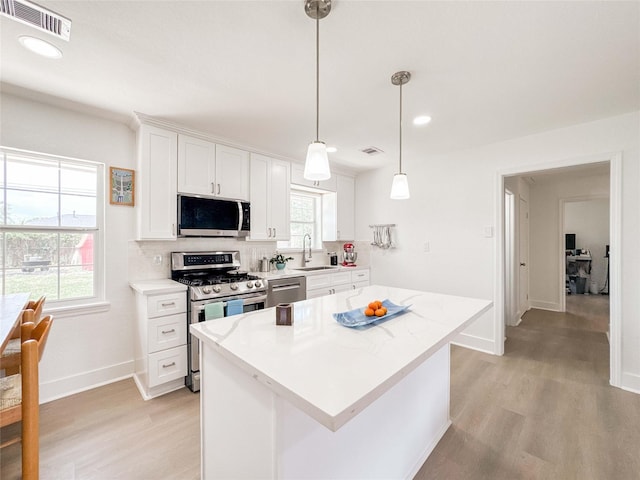 2302 Hewitt Dr, Houston, TX 77018 - kitchen with stainless steel appliances, light wood-style flooring, white cabinets, tasteful backsplash, and a sink
