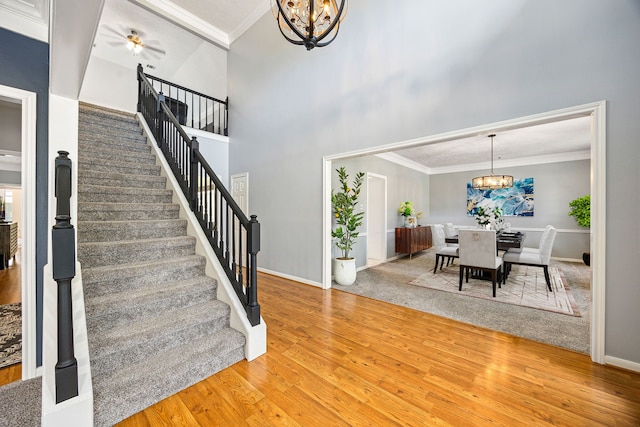24714 Valleylight Dr, Katy, TX 77494 - staircase featuring a chandelier, ornamental molding, wood finished floors, baseboards, and a towering ceiling