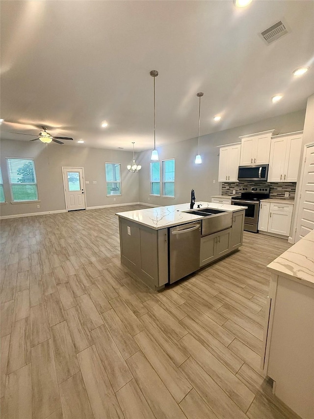 535 Longhorn Trl, Angleton, TX 77515 - kitchen with appliances with stainless steel finishes, open floor plan, a kitchen island with sink, a sink, and light wood-type flooring