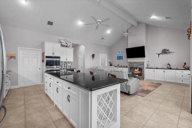 7014 Terrasso Dr, Hitchcock, TX 77563 - kitchen with dark countertops, double oven, ceiling fan, light tile patterned floors, and beam ceiling