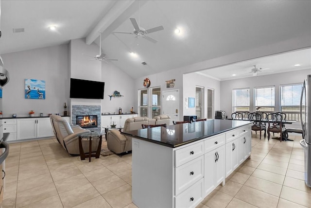 7014 Terrasso Dr, Hitchcock, TX 77563 - kitchen featuring ceiling fan, dark countertops, light tile patterned floors, beamed ceiling, and a glass covered fireplace
