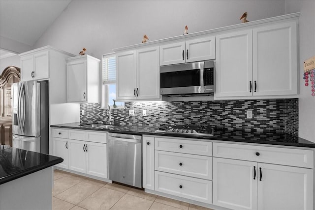 7014 Terrasso Dr, Hitchcock, TX 77563 - kitchen featuring appliances with stainless steel finishes, backsplash, a sink, white cabinetry, and lofted ceiling