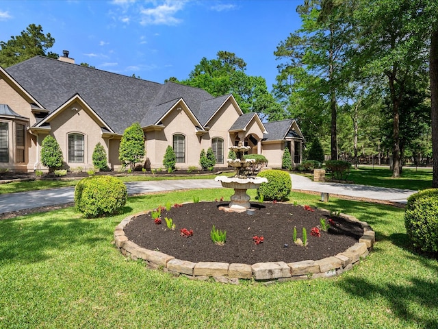 9819 Crestwater Cir, Magnolia, TX 77354 - french country inspired facade featuring a front yard, roof with shingles, curved driveway, and a chimney