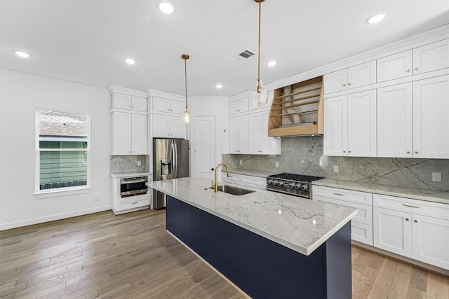 1316 E 34th St, Houston, TX 77022 - kitchen with a sink, appliances with stainless steel finishes, premium range hood, white cabinetry, and hanging light fixtures