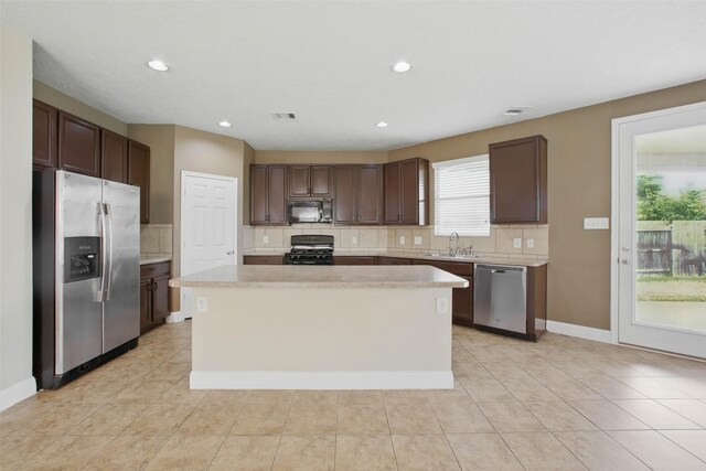 11707 Newel Elm St, Houston, TX 77038 - kitchen featuring appliances with stainless steel finishes, a sink, backsplash, light countertops, and a kitchen island