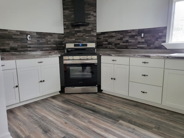 639 Manor St, Houston, TX 77015 - kitchen with stainless steel gas range, wall chimney exhaust hood, decorative backsplash, and white cabinets