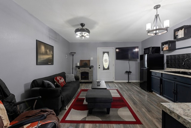 639 Manor St, Houston, TX 77015 - living room featuring a chandelier, dark wood-type flooring, a fireplace, and baseboards