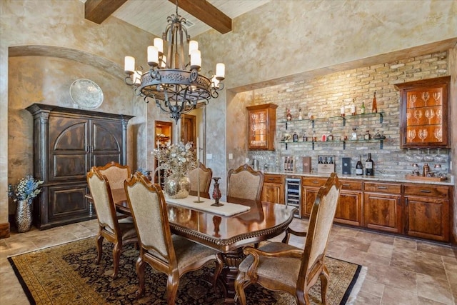 535 Creekside Dr, Salado, TX 76571 - dining space with wine cooler, beam ceiling, a chandelier, light stone finish flooring, and a high ceiling