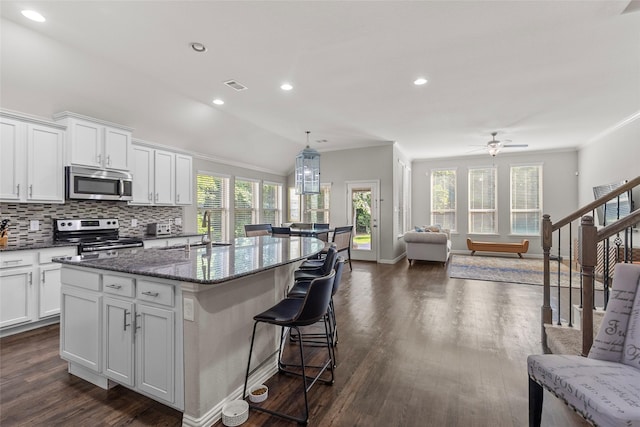 8992 S Comanche Cir, Willis, TX 77378 - kitchen with appliances with stainless steel finishes, a sink, open floor plan, a center island, and dark wood-type flooring