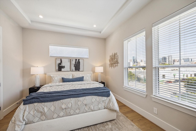 2208 Dennis St, Houston, TX 77004 - bedroom featuring multiple windows, light wood-type flooring, a tray ceiling, baseboards, and recessed lighting