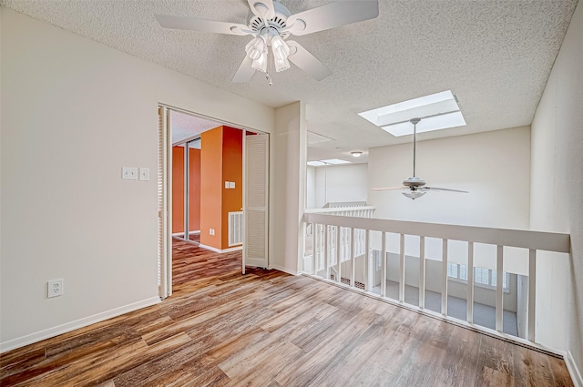 11605 Southlake Dr Unit 32, Houston, TX 77077 - spare room featuring a ceiling fan, a skylight, wood finished floors, a textured ceiling, and baseboards