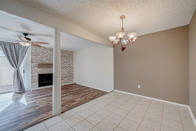 11605 Southlake Dr Unit 32, Houston, TX 77077 - unfurnished living room with a ceiling fan, light tile patterned flooring, a chandelier, a textured ceiling, and a brick fireplace