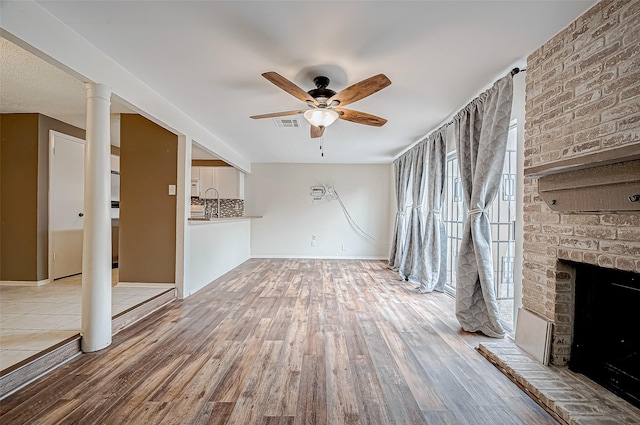 11605 Southlake Dr Unit 32, Houston, TX 77077 - unfurnished living room with wood finished floors, a ceiling fan, a brick fireplace, and baseboards