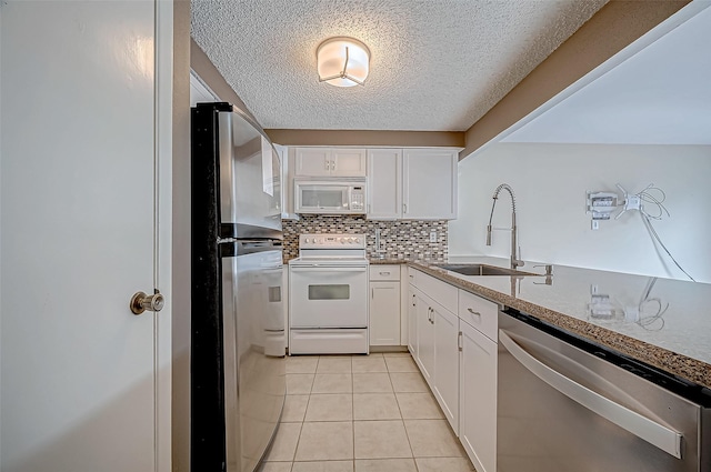 11605 Southlake Dr Unit 32, Houston, TX 77077 - kitchen featuring stainless steel appliances, a sink, white cabinetry, a textured ceiling, and decorative backsplash
