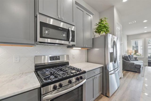 9013 Lonestar Creekbend Ln, Houston, TX 77080 - kitchen with appliances with stainless steel finishes, gray cabinetry, light wood finished floors, backsplash, and recessed lighting