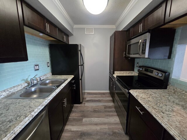 1860 White Oak Dr Unit 314, Houston, TX 77009 - kitchen featuring stainless steel appliances, a sink, tasteful backsplash, wood finished floors, and ornamental molding
