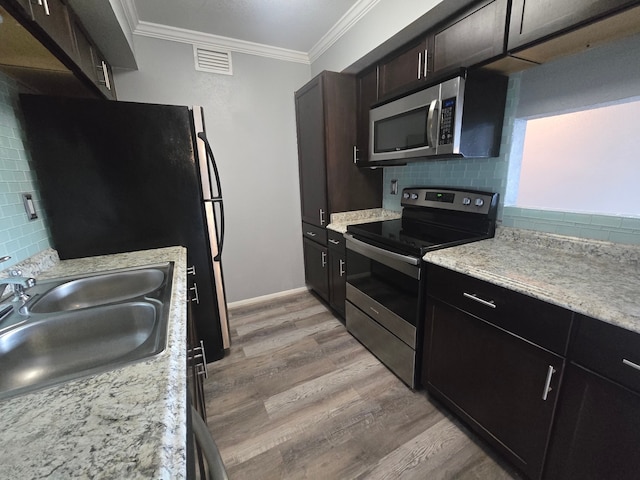 1860 White Oak Dr Unit 314, Houston, TX 77009 - kitchen featuring appliances with stainless steel finishes, light wood-style floors, a sink, backsplash, and ornamental molding