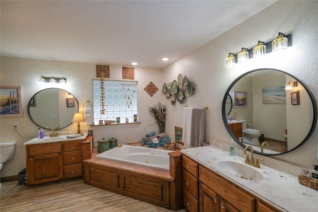 4746 County Road 502d, Sweeny, TX 77480 - full bath featuring toilet, wood finished floors, two vanities, a whirlpool tub, and a textured wall