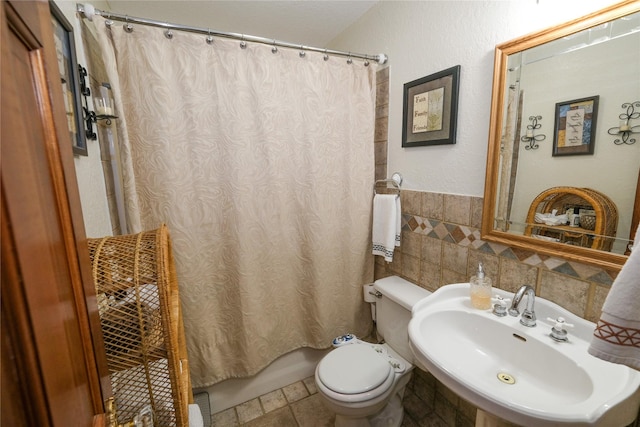 4746 County Road 502d, Sweeny, TX 77480 - bathroom with a sink, toilet, a wainscoted wall, tile walls, and shower / tub combo