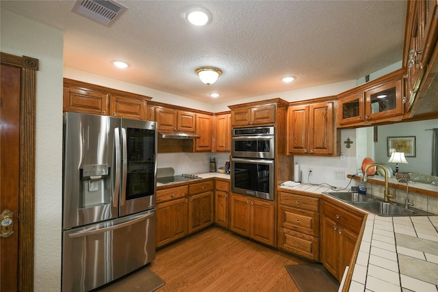 4746 County Road 502d, Sweeny, TX 77480 - kitchen featuring stainless steel appliances, tile countertops, a sink, under cabinet range hood, and brown cabinets