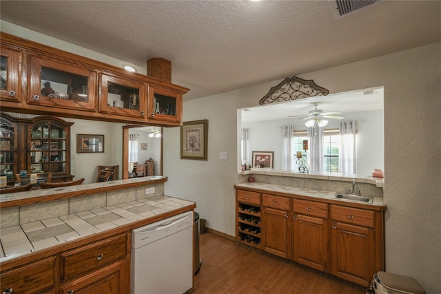 4746 County Road 502d, Sweeny, TX 77480 - kitchen featuring tile counters, a sink, dishwasher, light wood-style flooring, and a textured ceiling