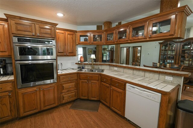 4746 County Road 502d, Sweeny, TX 77480 - kitchen featuring dishwasher, a sink, stainless steel double oven, brown cabinetry, and tile counters