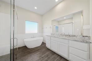 9314 Brunel Ln, Houston, TX 77044 - full bathroom featuring double vanity, a stall shower, a freestanding bath, wood finished floors, and recessed lighting