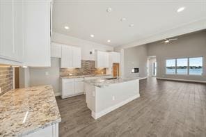 9314 Brunel Ln, Houston, TX 77044 - kitchen with white cabinets, tasteful backsplash, an island with sink, open floor plan, and dark wood-style floors