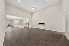 9314 Brunel Ln, Houston, TX 77044 - unfurnished living room featuring dark wood-style flooring, high vaulted ceiling, baseboards, and ceiling fan