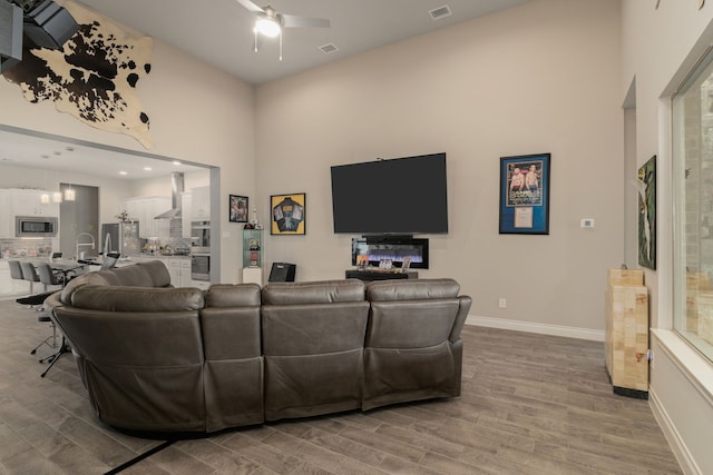 9314 Brunel Ln, Houston, TX 77044 - living room featuring light wood-type flooring, ceiling fan, and a high ceiling