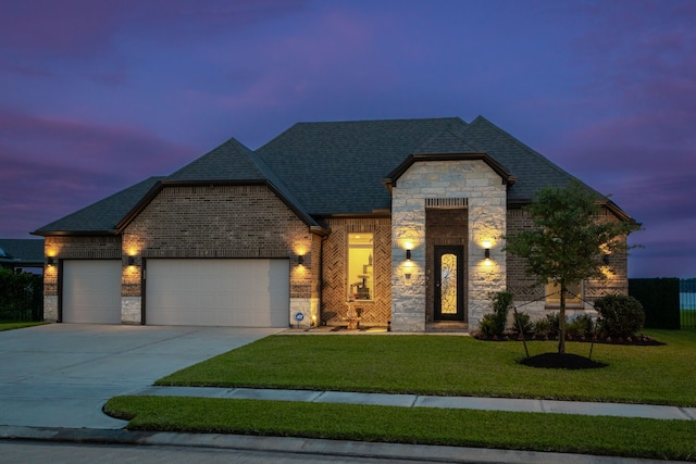 9314 Brunel Ln, Houston, TX 77044 - french provincial home featuring an attached garage, stone siding, driveway, brick siding, and a front lawn
