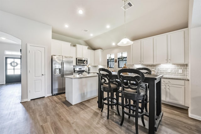 5307 Cascade Ct, Alvin, TX 77511 - kitchen featuring appliances with stainless steel finishes, decorative backsplash, a kitchen island, arched walkways, and white cabinets