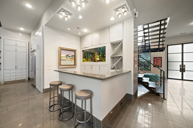 507 Terrace Dr, Houston, TX 77007 - kitchen with baseboards, white cabinetry, recessed lighting, a breakfast bar area, and tile patterned floors