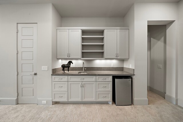 507 Terrace Dr, Houston, TX 77007 - kitchen with stainless steel refrigerator, light colored carpet, open shelves, a sink, and baseboards