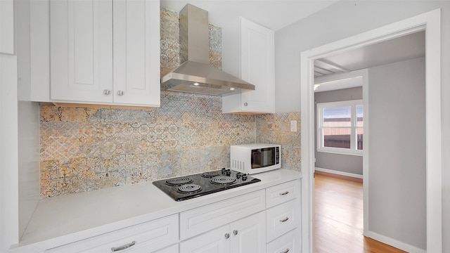 6805 Mobud Dr, Houston, TX 77074 - kitchen featuring wall chimney exhaust hood, white microwave, black electric stovetop, backsplash, and light countertops