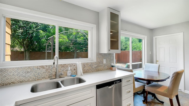 6805 Mobud Dr, Houston, TX 77074 - kitchen featuring stainless steel dishwasher, a sink, decorative backsplash, light countertops, and glass insert cabinets