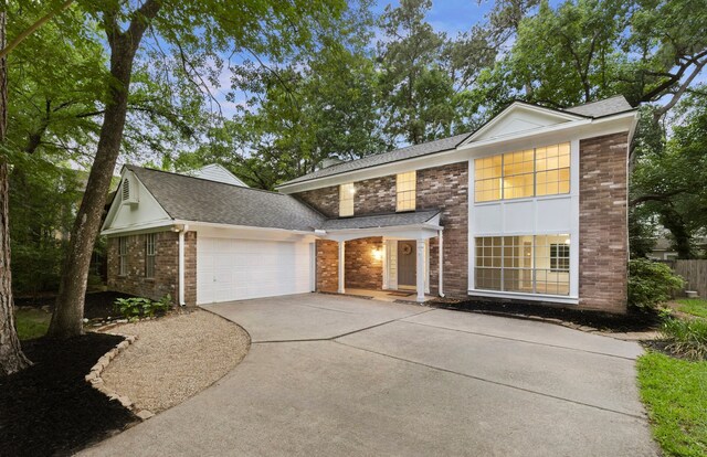 150 Rushwing Pl, The Woodlands, TX 77381 - view of front of property featuring a garage, concrete driveway, a shingled roof, and brick siding