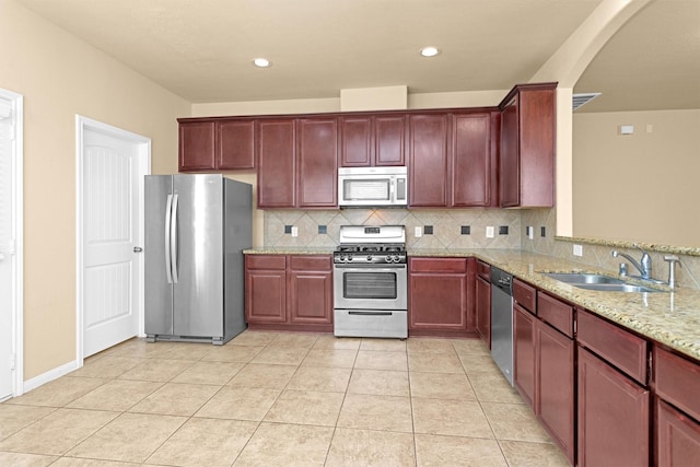 24734 Colonial Maple Dr, Katy, TX 77493 - kitchen with stainless steel appliances, a sink, dark brown cabinets, arched walkways, and light stone counters