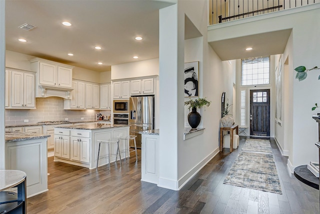 705 Serenity View Ln, Katy, TX 77493 - kitchen with stainless steel appliances, dark wood finished floors, light stone counters, tasteful backsplash, and a kitchen island