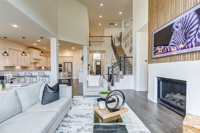 705 Serenity View Ln, Katy, TX 77493 - living area with wood finished floors, stairs, a towering ceiling, a glass covered fireplace, and recessed lighting