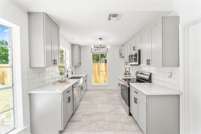10530 Tenneco Dr, Houston, TX 77099 - kitchen featuring appliances with stainless steel finishes, light marble finish flooring, light countertops, a sink, and backsplash