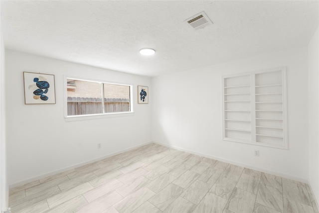 10530 Tenneco Dr, Houston, TX 77099 - empty room featuring a textured ceiling, built in shelves, and baseboards