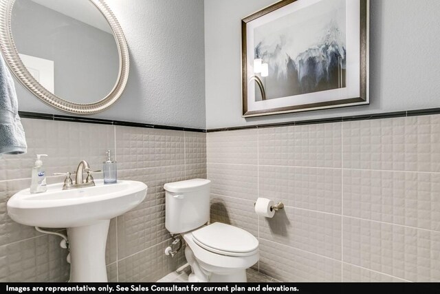 804 Wormwood Dr, League City, TX 77573 - half bathroom featuring tile walls, toilet, and wainscoting