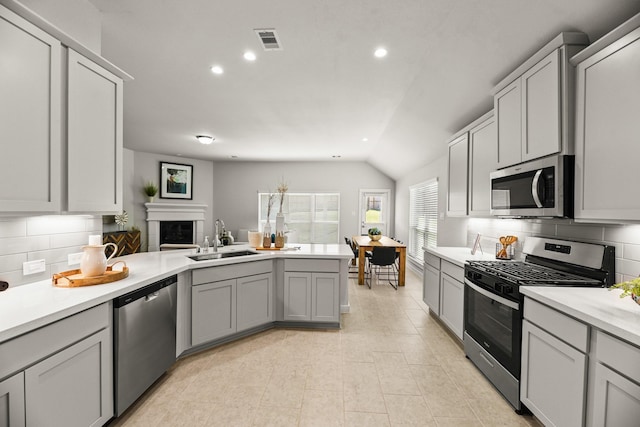104 Dina Ln, Montgomery, TX 77356 - kitchen featuring appliances with stainless steel finishes, a sink, a peninsula, tasteful backsplash, and lofted ceiling